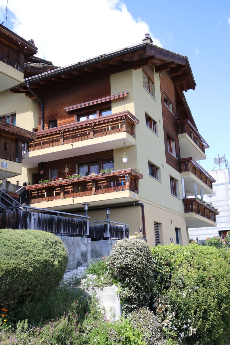 apartment building, balconies, large windows, wooden exterior, multiple floors, garden, fence