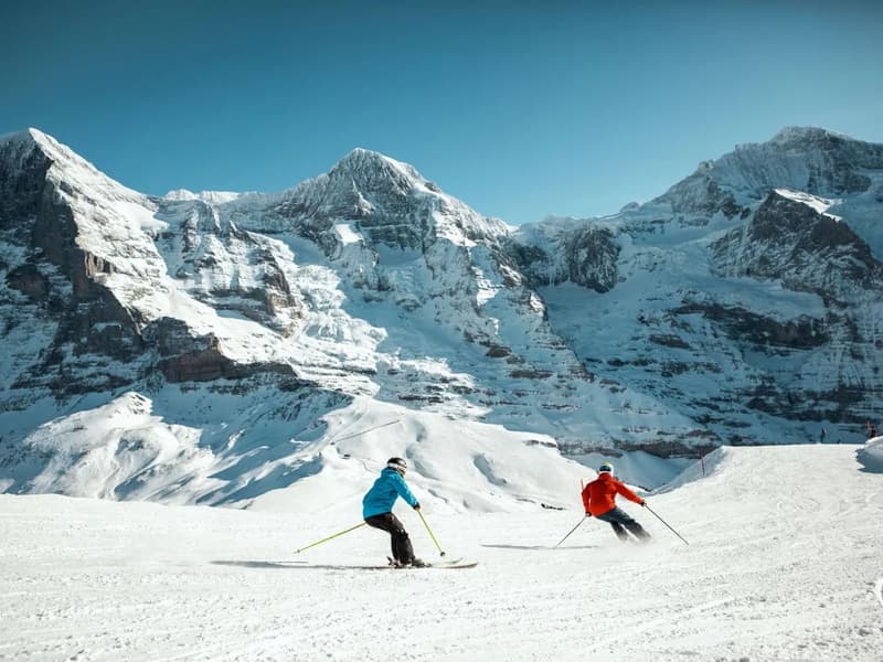 Two skiers on a snowy mountain slope with a view of the mountains