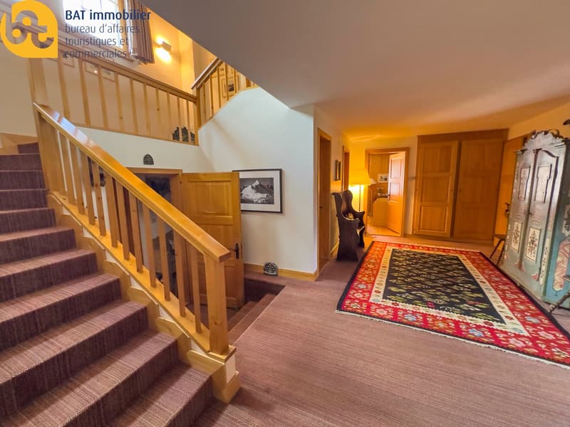 Wooden staircase, hardwood floors, patterned area rug, wooden doors, wall decor
