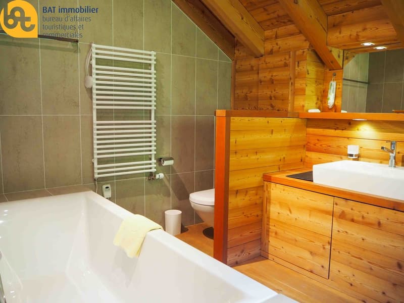 Bathroom with wooden walls and ceiling, white bathtub, white towel rack, and a vanity with a sink