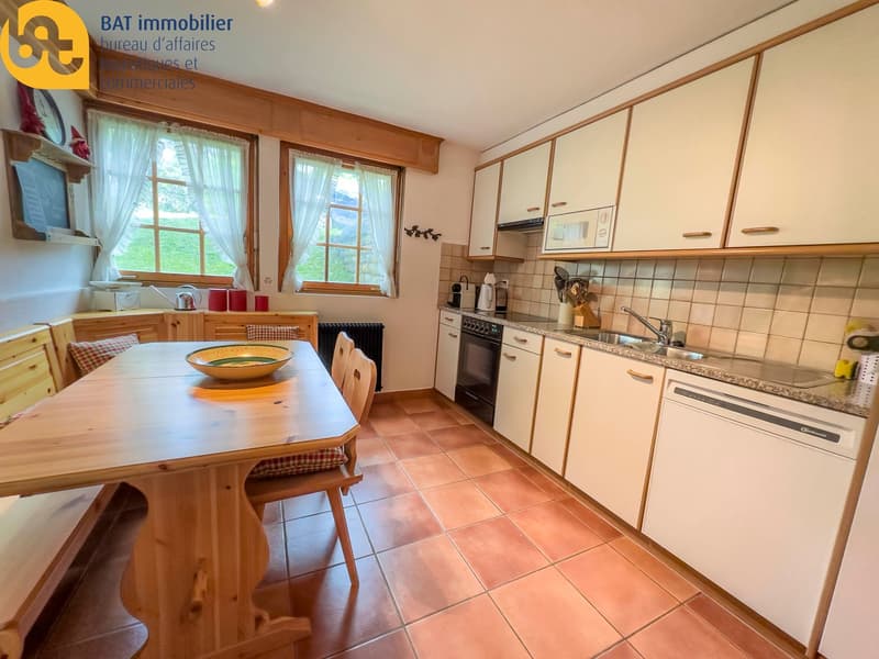 Spacious kitchen with wooden cabinets, tile flooring, dining table, and appliances including a dishwasher