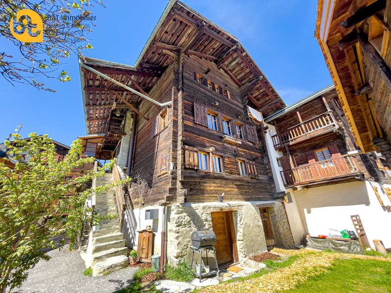 2-story wooden chalet-style house with stone foundation, balconies, and a parking area in the front