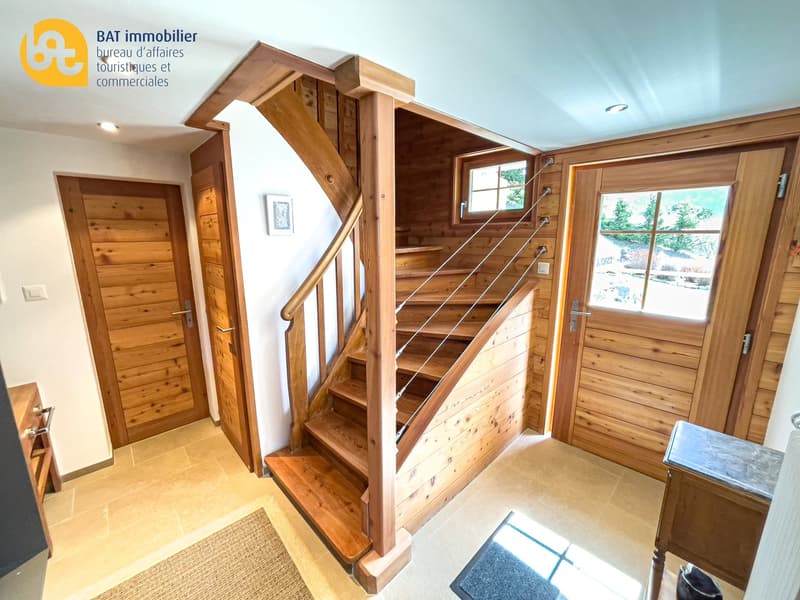 Wooden staircase with railing, wooden doors and windows, tiled floor, open space layout