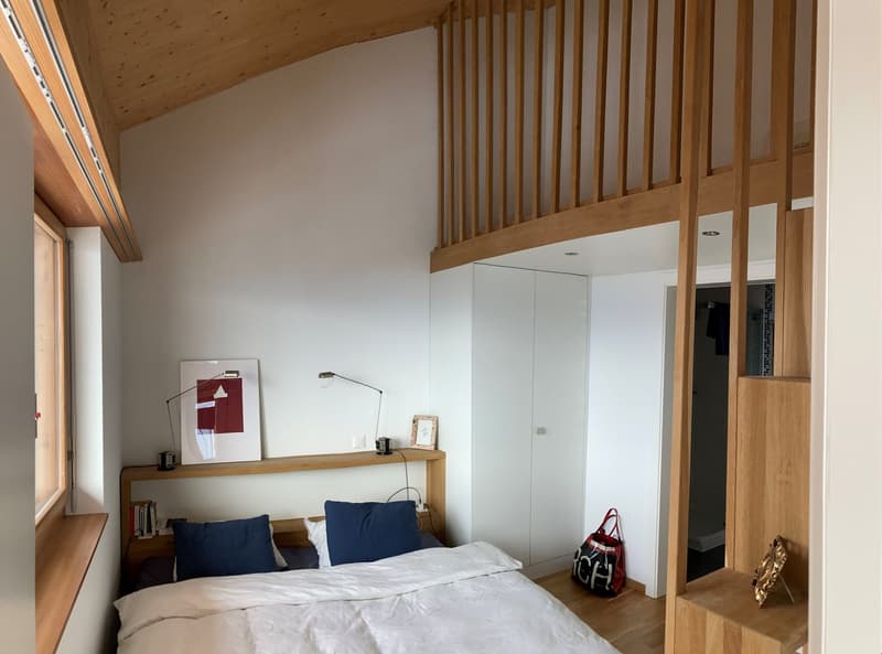 large bed, wooden shelves, white walls, window with wooden sill, lamps, picture frame, red bag