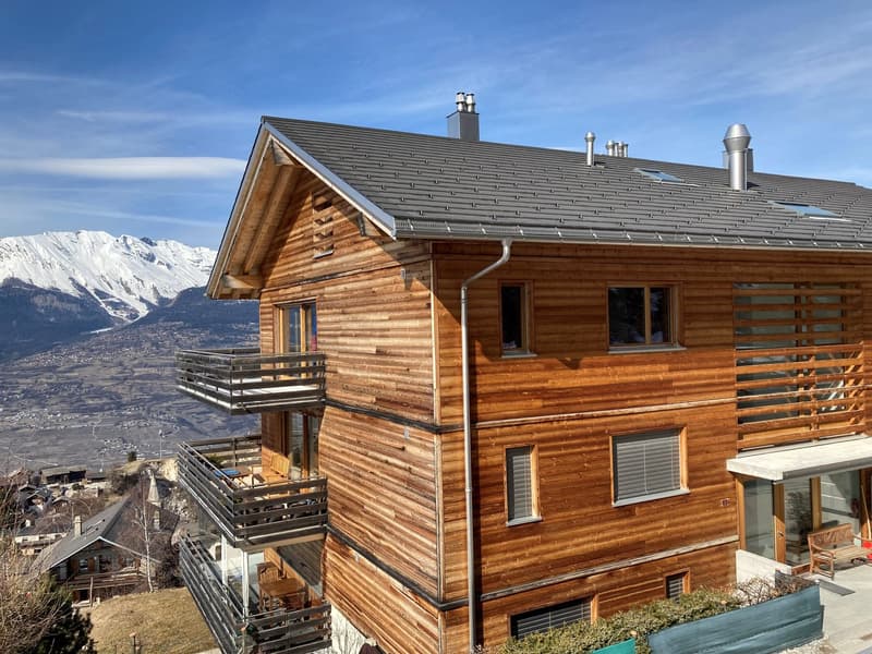 3-story wooden chalet, multiple balconies, chimney, solar panels on roof, mountains in background