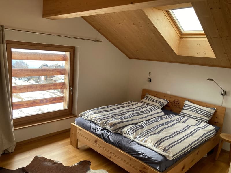 bedroom with wooden bed, wooden floor, large window, wooden ceiling, wooden nightstand, wooden wall lamps