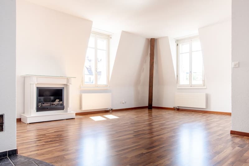 empty room, wooden floor, fireplace, two windows, white walls, radiators
