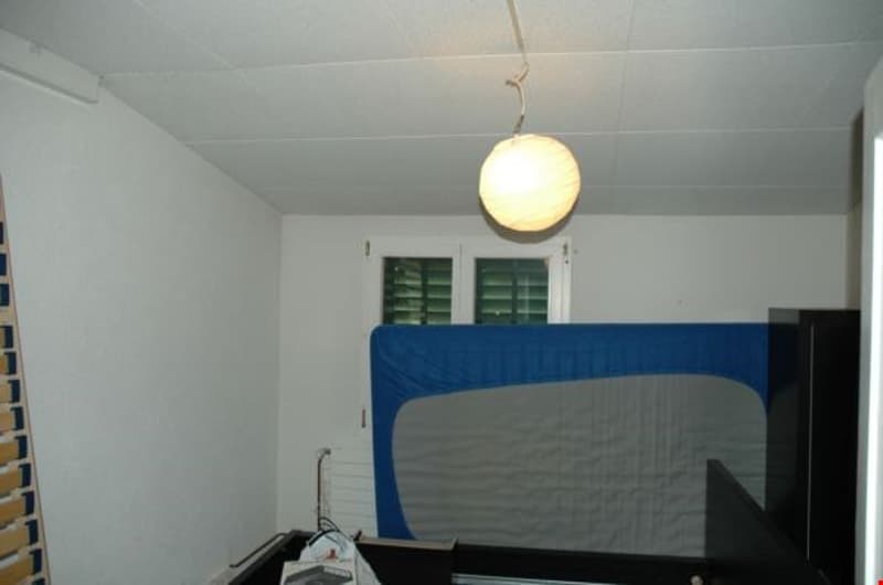 white walls, white ceiling, blue and gray bed, white window, hanging lamp