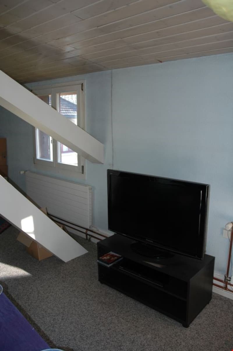 room with a television, a radiator, a window, and a staircase