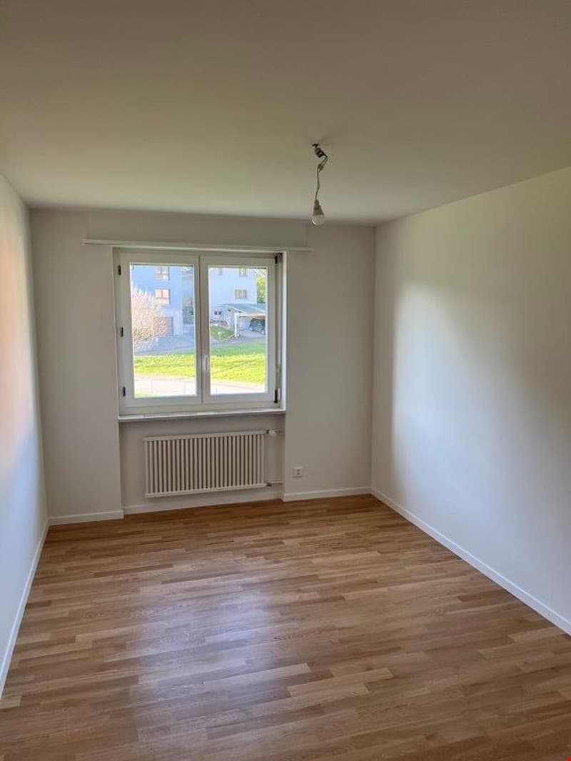 Empty room with white walls, hardwood flooring, and a window overlooking the exterior.