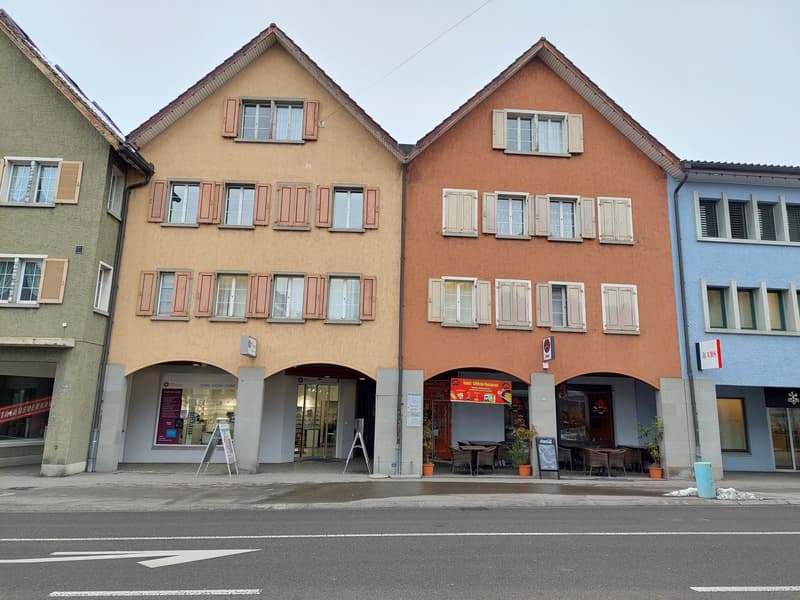 Apartment building with three floors, multiple windows, entrance, restaurant area