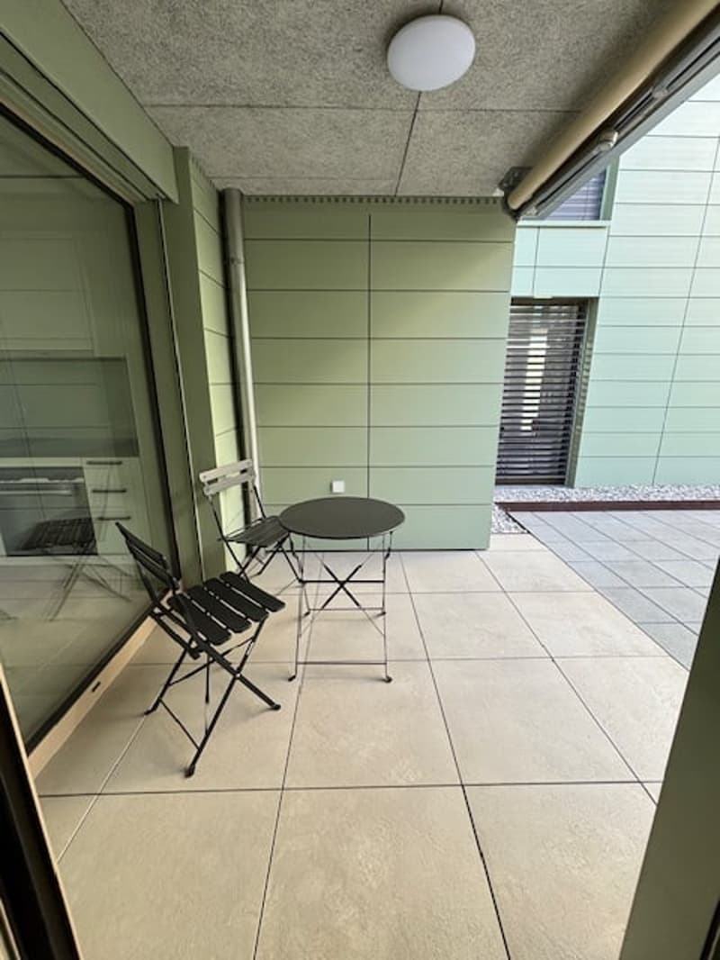 Balcony with table and chairs, tiled floor, glass door, green walls