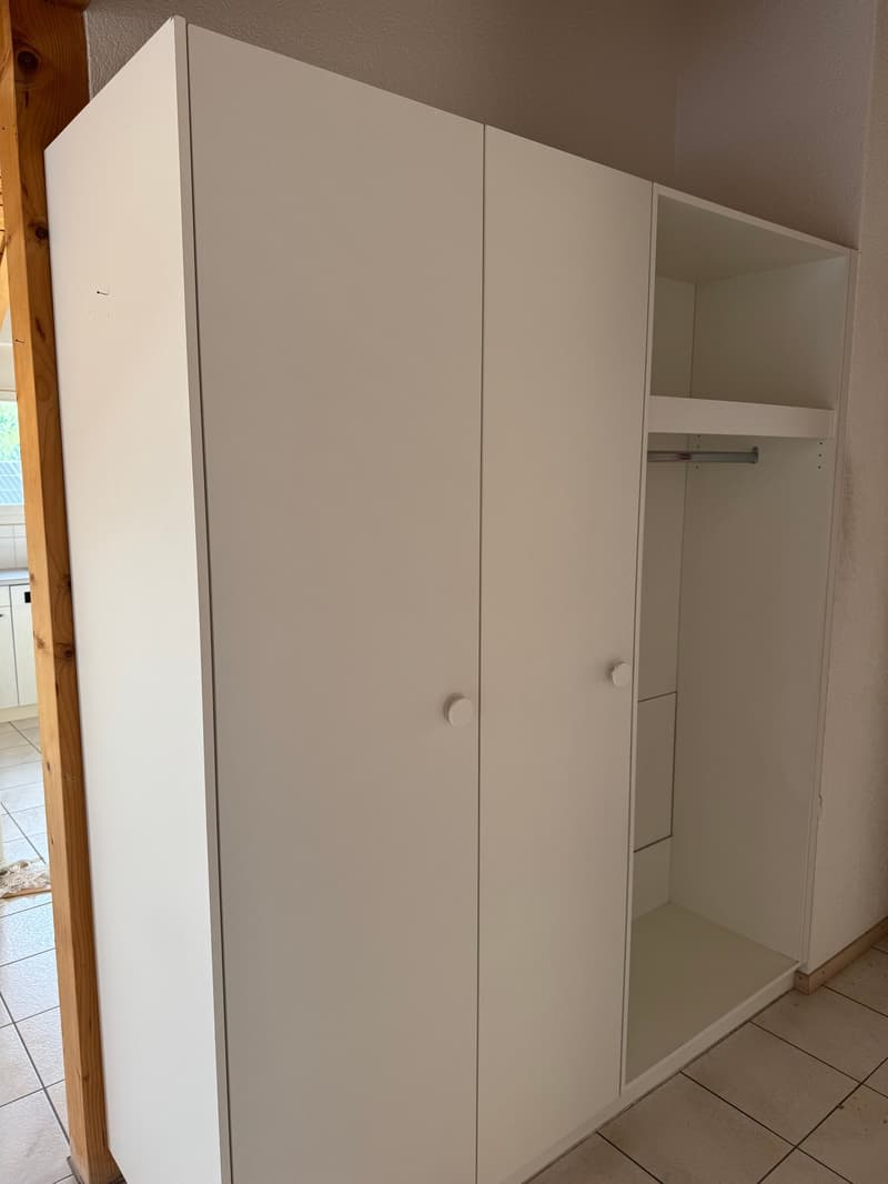 White, three-door wardrobe, two sections with doors, one section with a hanging bar