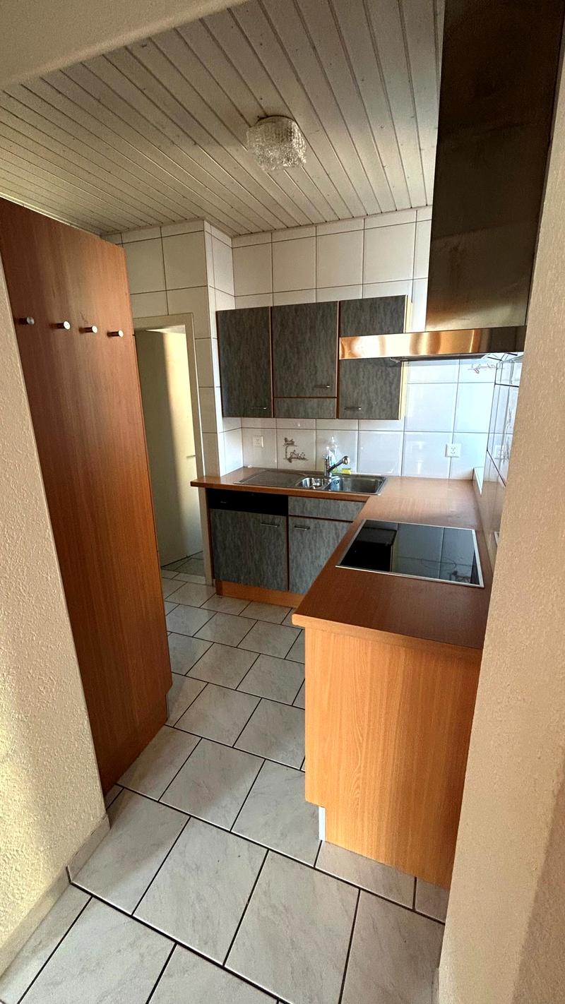Kitchen with white tiles, wooden cabinets, gas stove, sink, dishwasher, cabinets with hooks, ceiling lamp