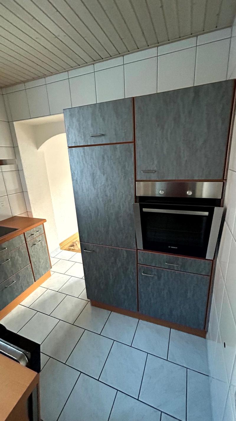 Large kitchen with built-in oven, cabinets, washing machine, dishwasher, and tiled floor.