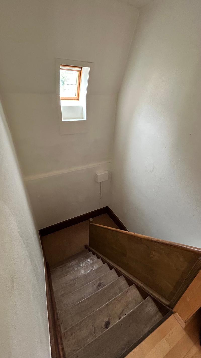 interior staircase with wooden railing, single attic window