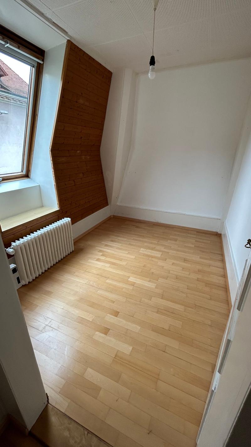 Empty room, wooden floor, radiator, attic, slanted ceiling, window with bench, ceiling light