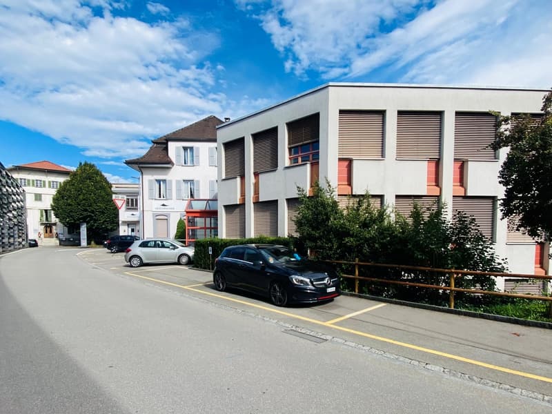 Modern building with parking area and a few cars parked