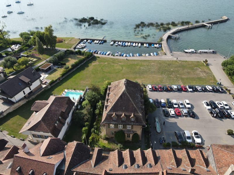Aerial view of property with swimming pool, large building, parking lot