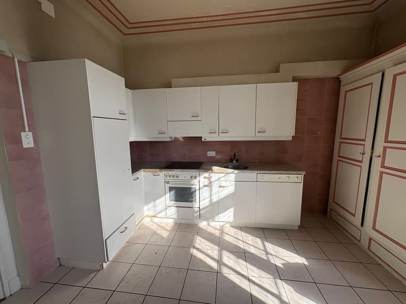 Fully furnished kitchen, white cabinets, modern appliances, tiled floor, red tiles on wall