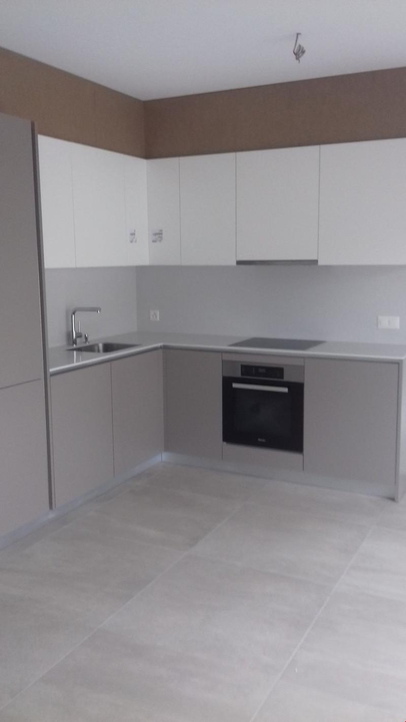 Modern kitchen with white cabinets, stainless steel appliances including a dishwasher, and tile flooring.