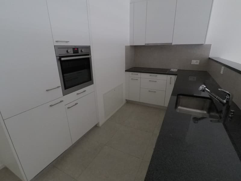 Modern kitchen with white cabinets, granite countertop, stainless steel sink, built-in oven, and dishwasher