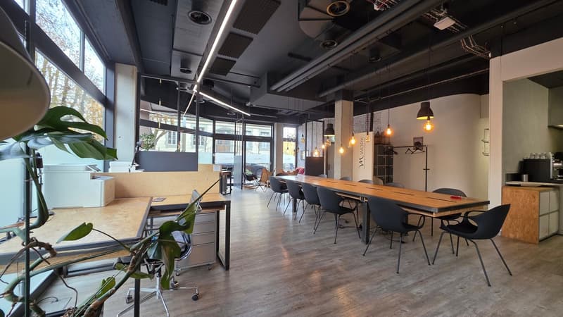 Large meeting room with wooden table, glass doors, chairs, and hanging lamps.