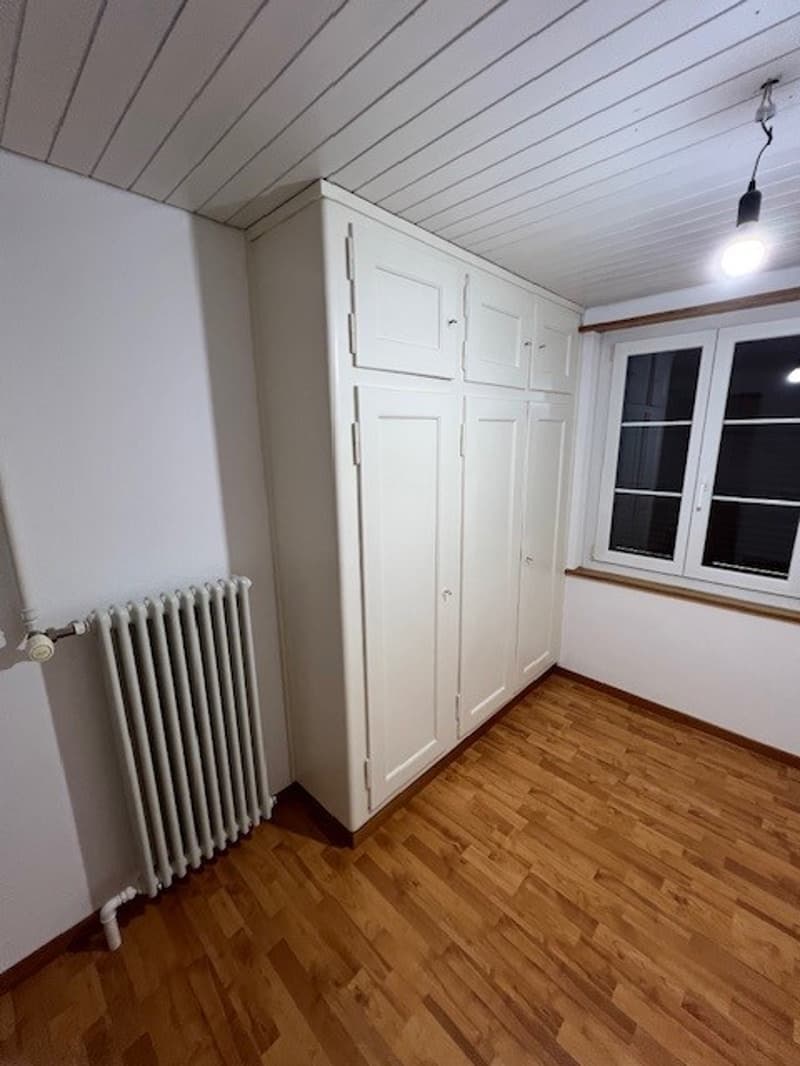 room with white wardrobe, radiator, and window with outside view