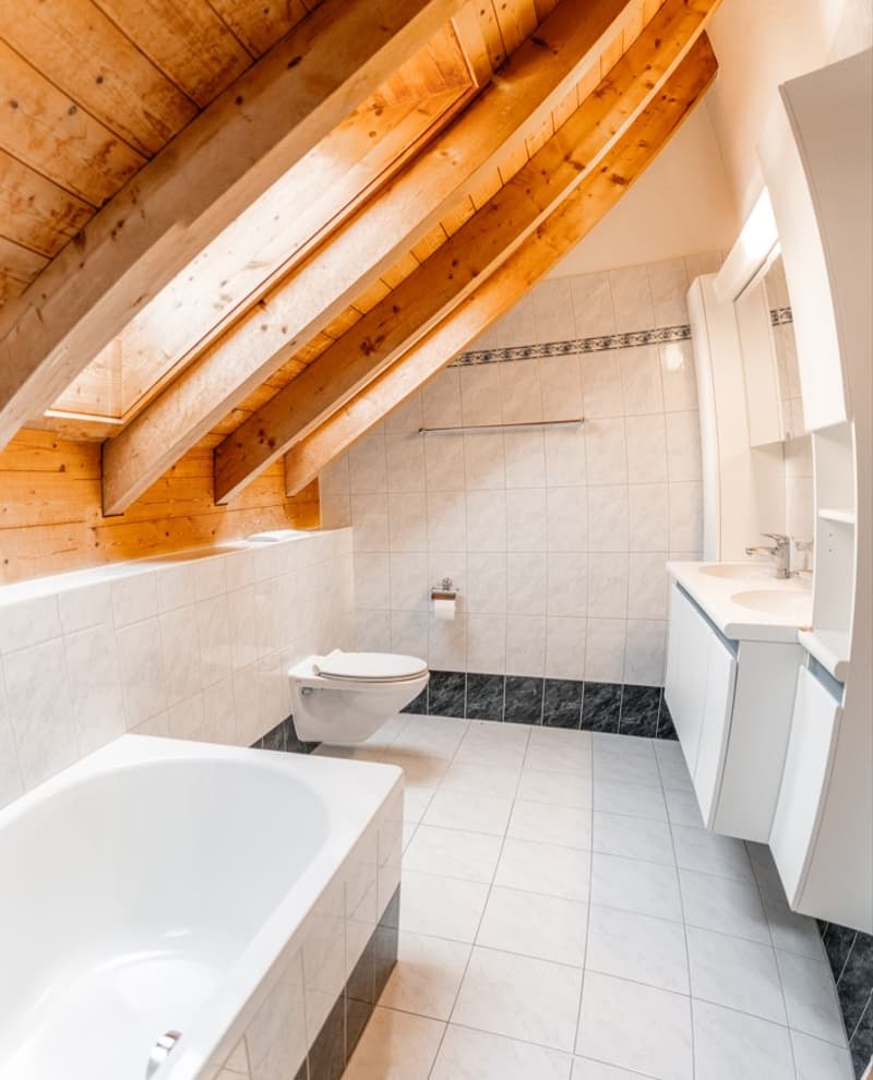 Bathroom with wooden ceiling, white bathtub, white toilet, white sink, white cabinets, white tiles, black tiles on the floor