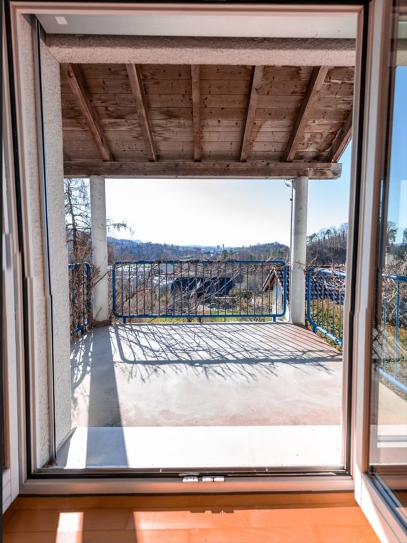 Balcony with wooden ceiling, blue railings, wooden floor, view of the landscape