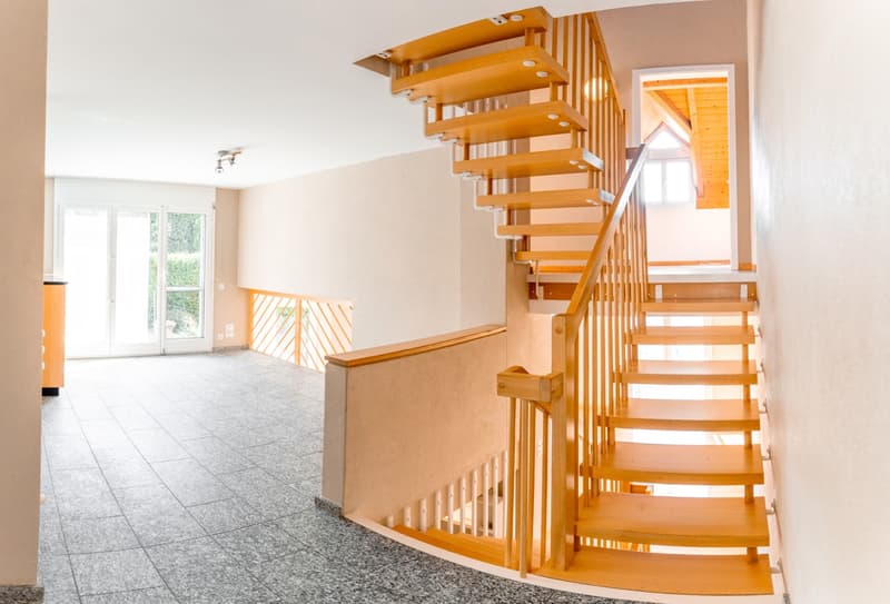 Empty room with wooden spiral staircase, tiled floor, glass doors, and ceiling lights