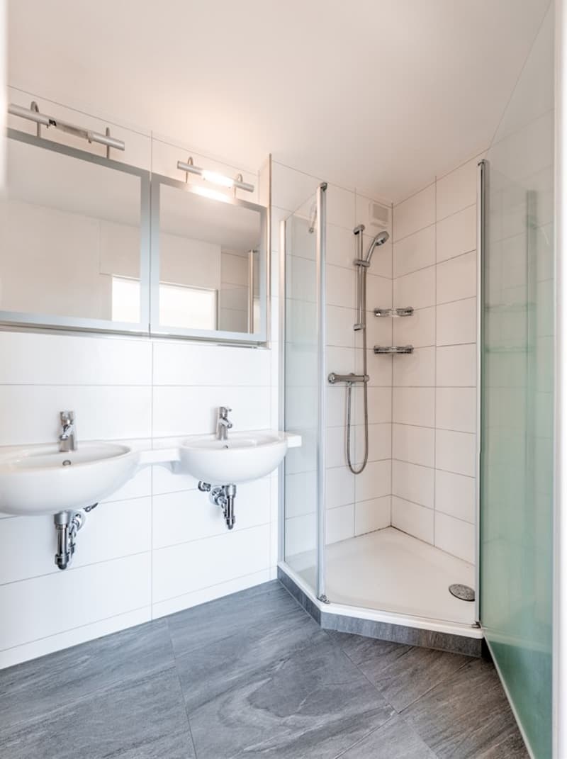 modern bathroom with two sinks, shower, and mirrors