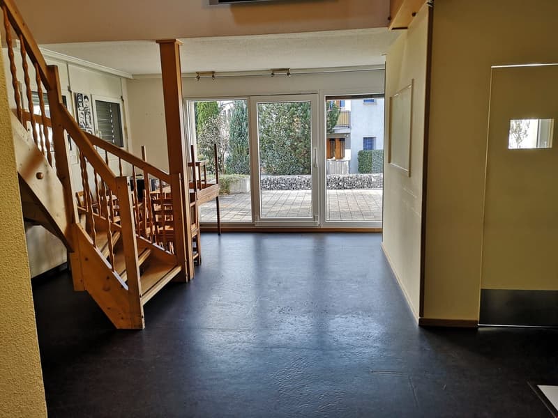 wooden stairs, glass door to terrace, beige walls, black floors, lamps on the ceiling