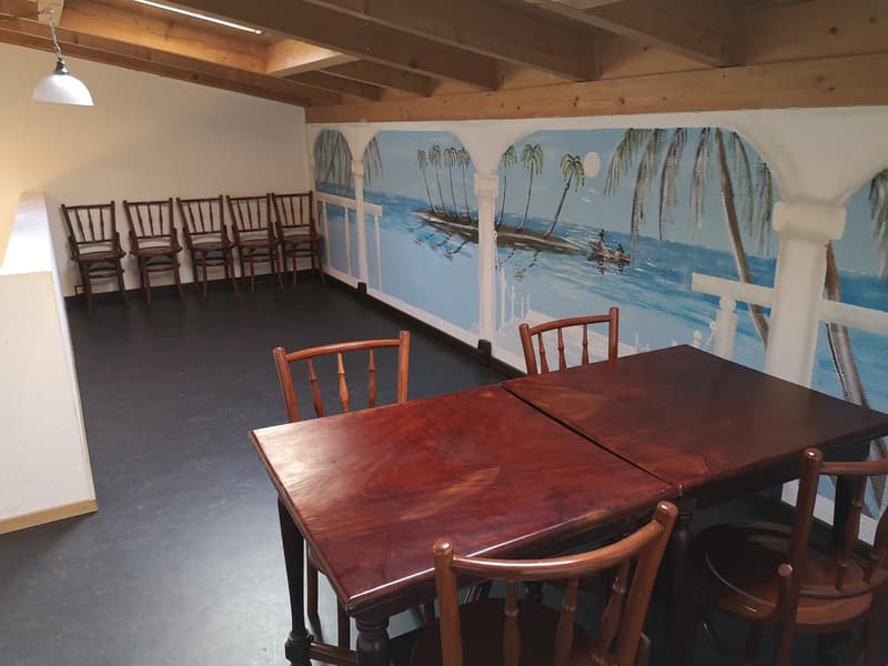 Wooden tables and chairs, tropical mural on the wall, exposed wooden beams, white walls, hanging lamp
