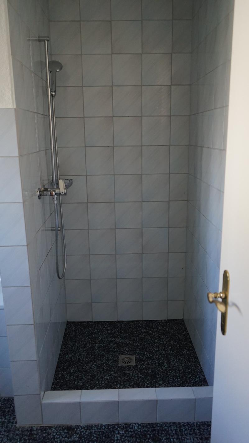 modern walk-in shower with white tiles, black floor, modern showerhead