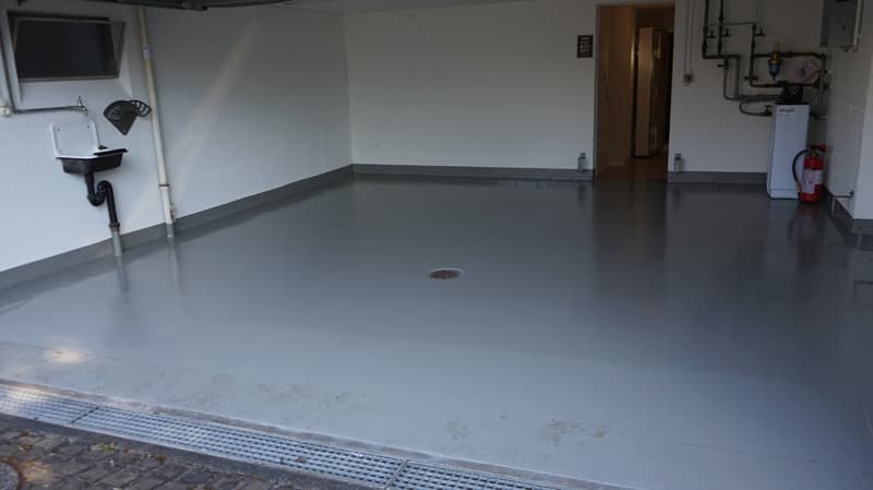 A concrete floored room with sink and fire extinguisher, empty