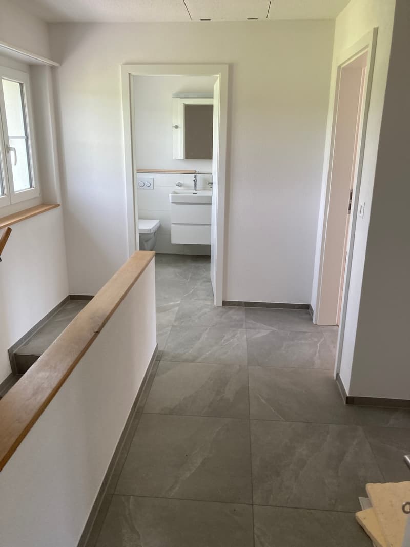 Corridor with tiled floor, opening to bathroom with toilet, sink, mirror and bathtub