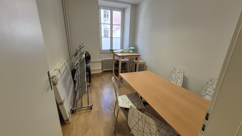 empty room, wooden floor, white walls, large window, table, chairs, radiator, fan