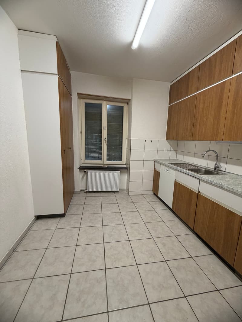 empty kitchen with white tiles, wooden cabinets, white appliances, window with blinds, radiator
