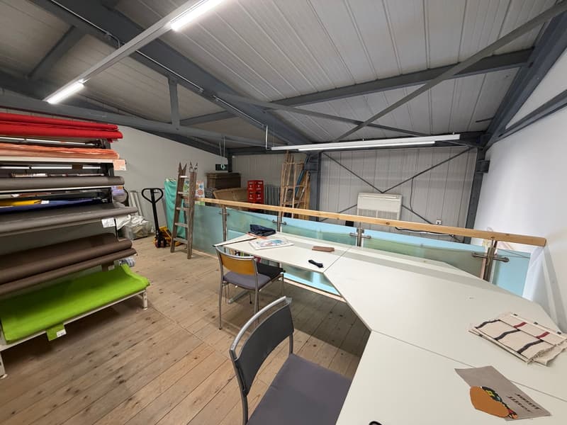 workspace with tables, chairs, ladder, roll of materials, glass walls, lights