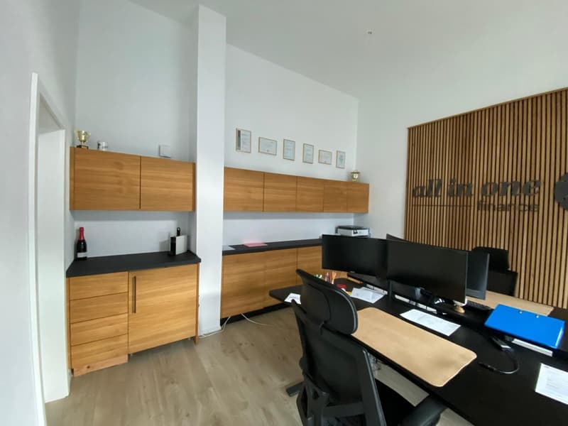 modern office with wooden cabinets, black desk, 2 monitors, black office chair, wooden floor