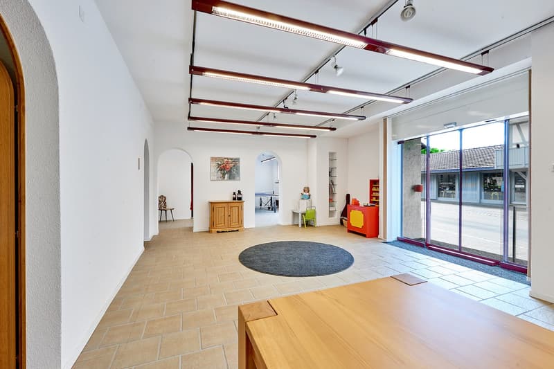 empty room, white walls, white tiles, a wooden table, a rug, a cabinet, lamps, sliding doors