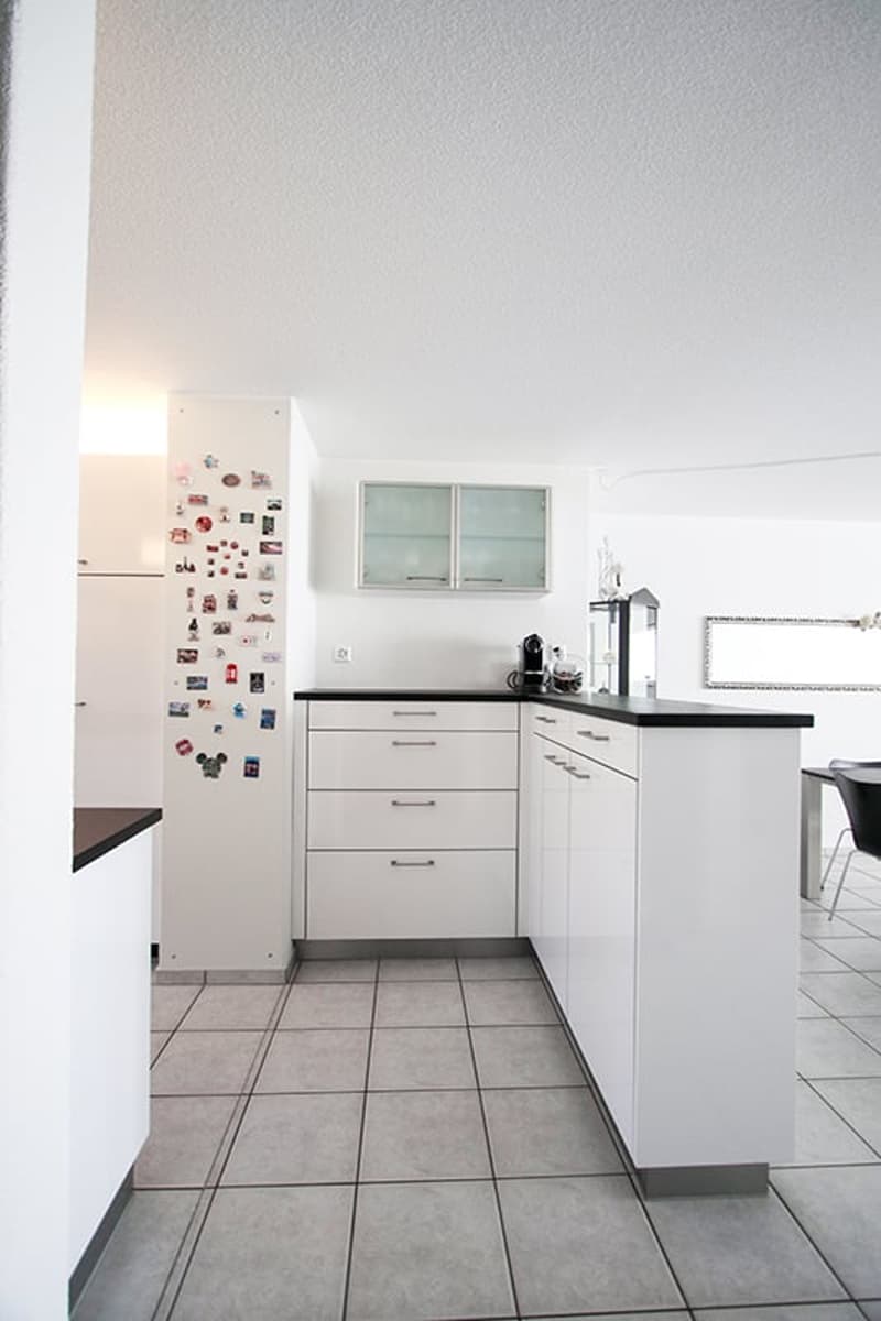 Kitchen with white cabinets and appliances, tiled floor, refrigerator, and countertop