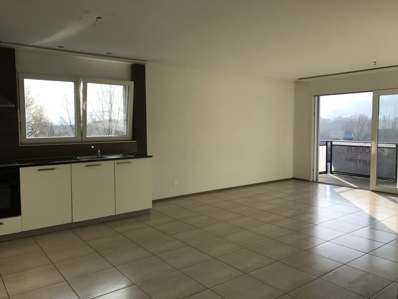 Empty kitchen with white cabinets, tiled floor, sink, faucet, windows, balcony with glass doors
