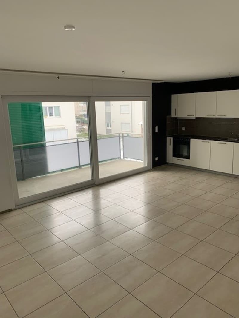 empty room, sliding glass door, balcony, tiled floor, white cabinets, black countertop