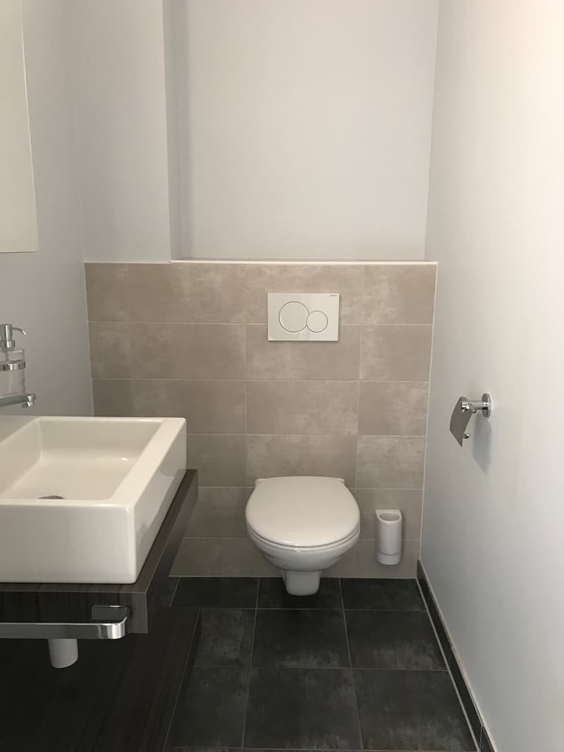 small bathroom with white sink, white toilet, and tiled walls