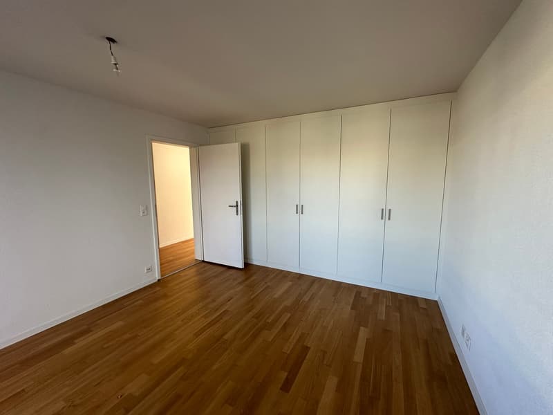 room with white walls, wooden floors, large closets, open door
