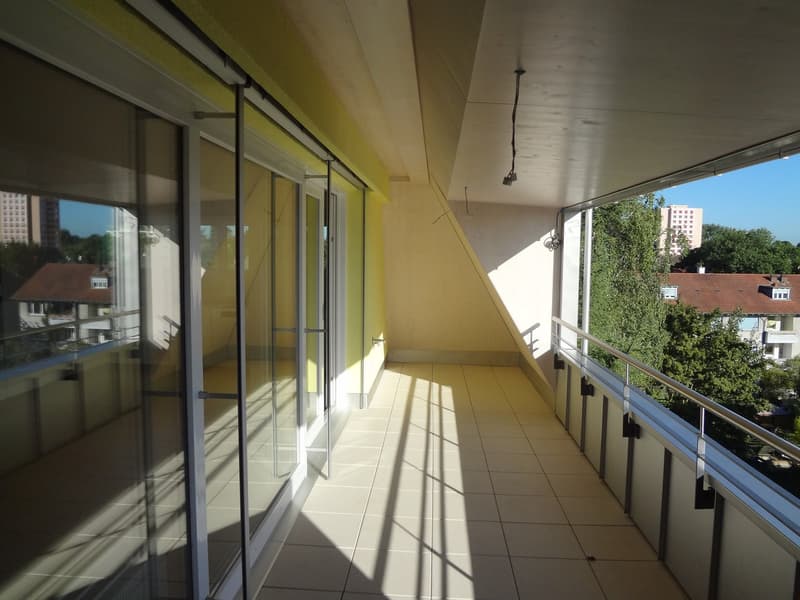 Balcony with white tiles, glass sliding doors, and metal railings