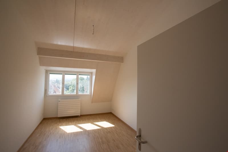 empty room with wooden floor, radiator, window