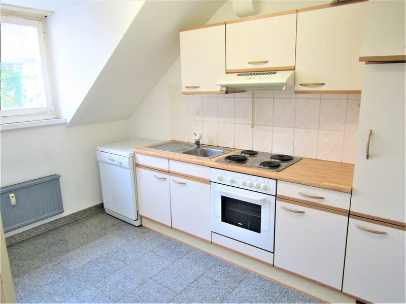 Kitchen with white cabinets, stove, sink, dishwasher, and a window.